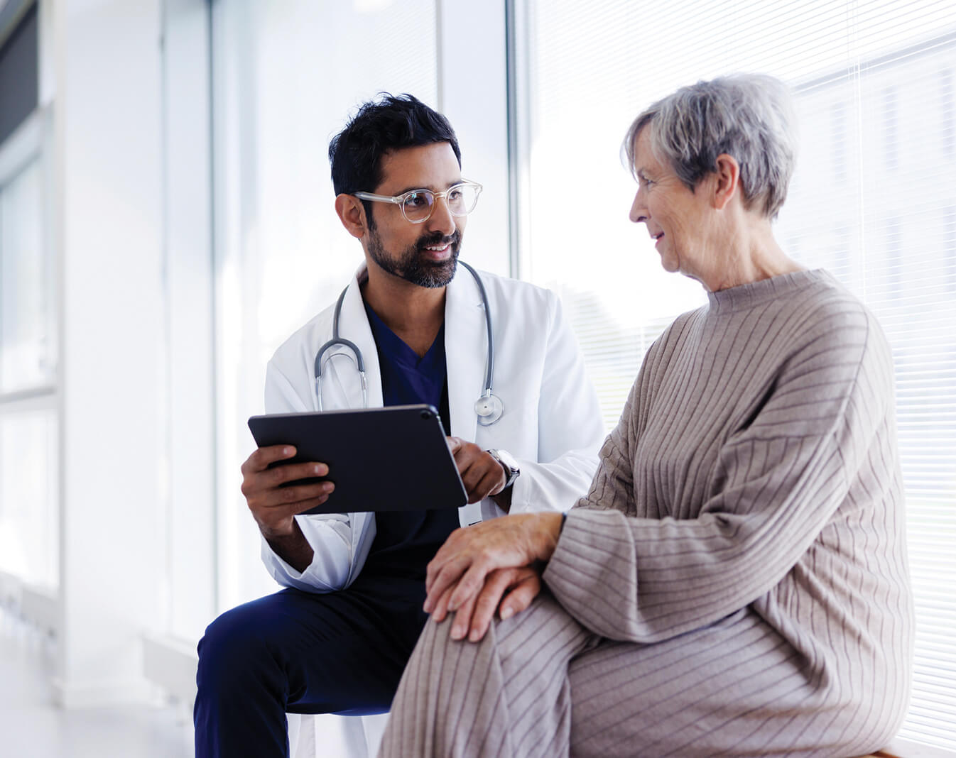 Doctor discussing information with an elderly patient in a bright, modern medical office.