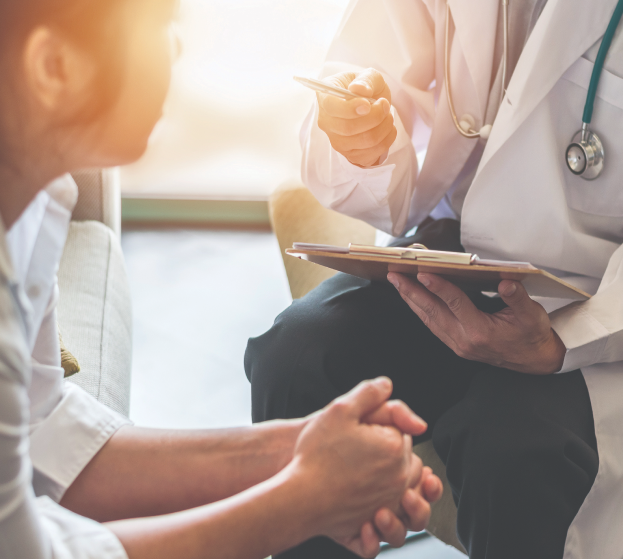 Doctor discussing medical information with a patient, holding a tablet and gesturing.